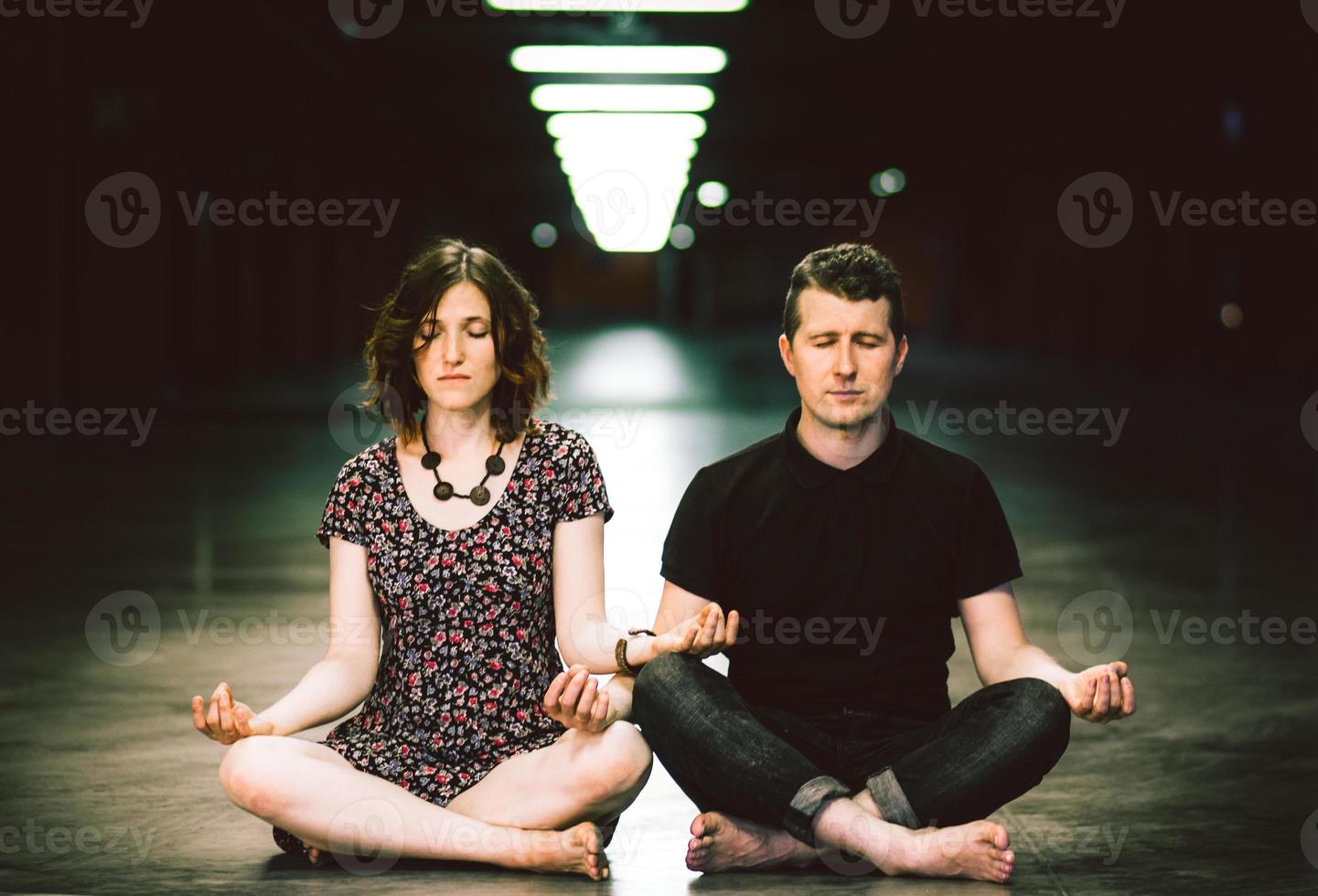 jovem casal meditando juntos sentado no estacionamento foto