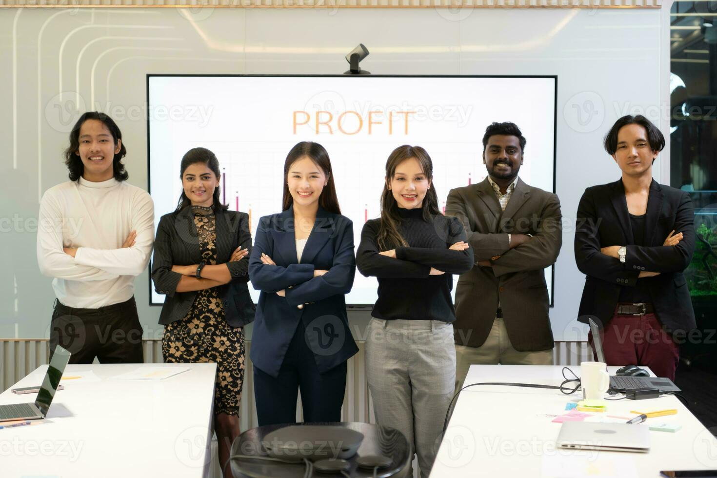 uma grupo do multirracial pessoas de negócio em pé com braços cruzado dentro frente do a encontro sala, indicando a conceito do o negócio sucesso. foto