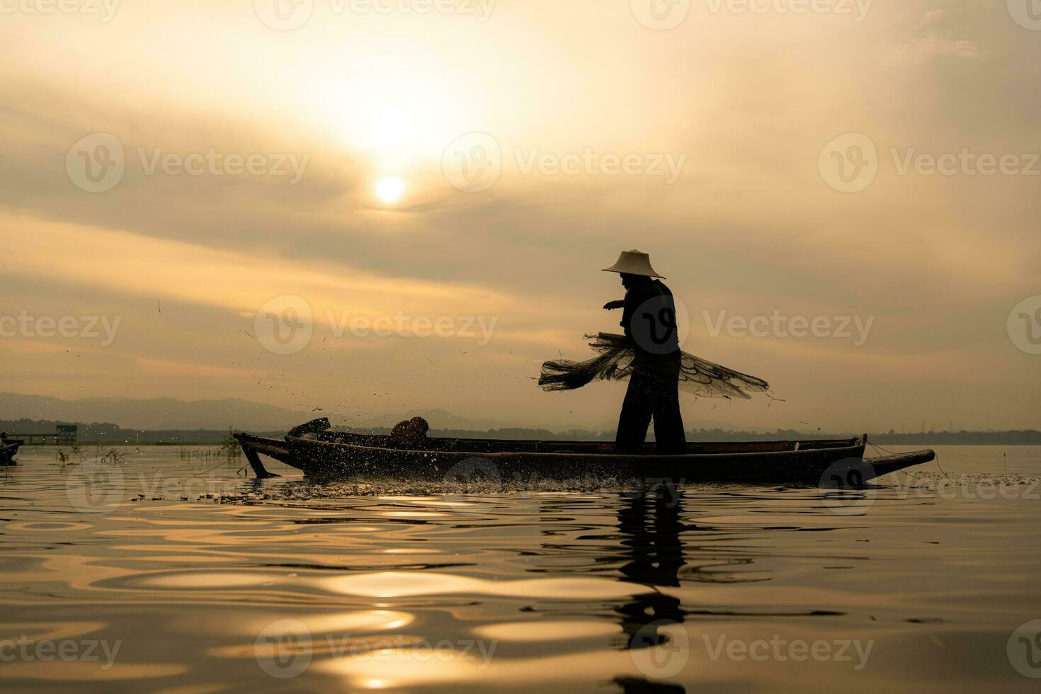 silhueta do pescador às nascer do sol, em pé a bordo uma remo barco e fundição uma internet para pegar peixe para Comida foto
