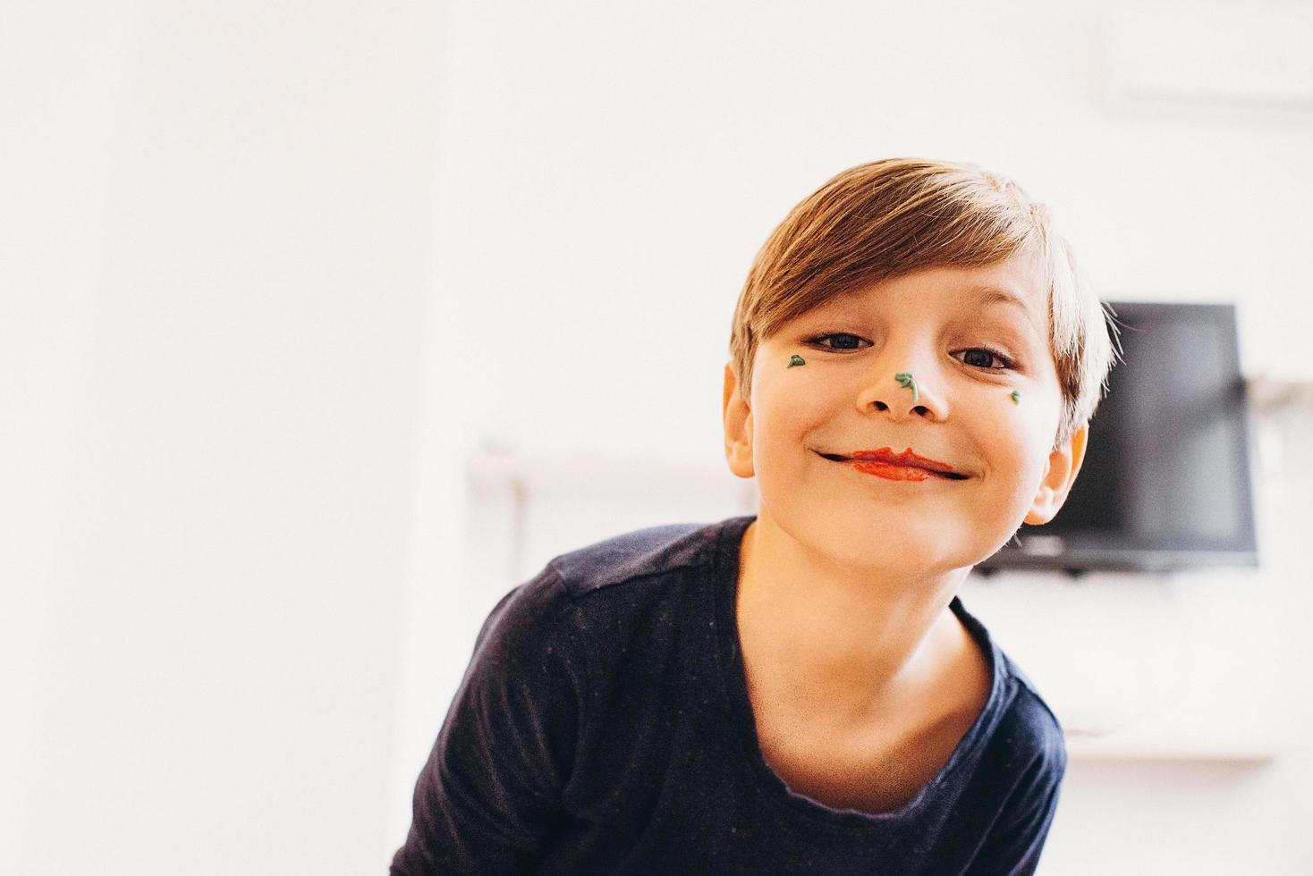 menino bonito com um rosto pintado de palhaço, sorrindo foto
