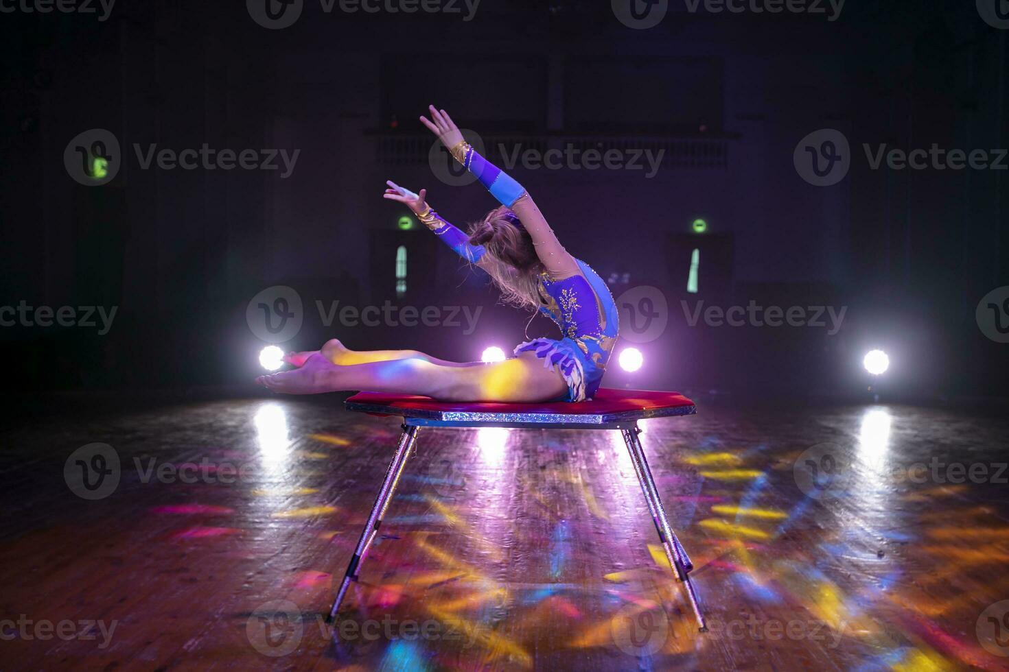 uma pequeno menina circo artista com uma flexível corpo executa em estágio. a criança do a equilibrista. foto