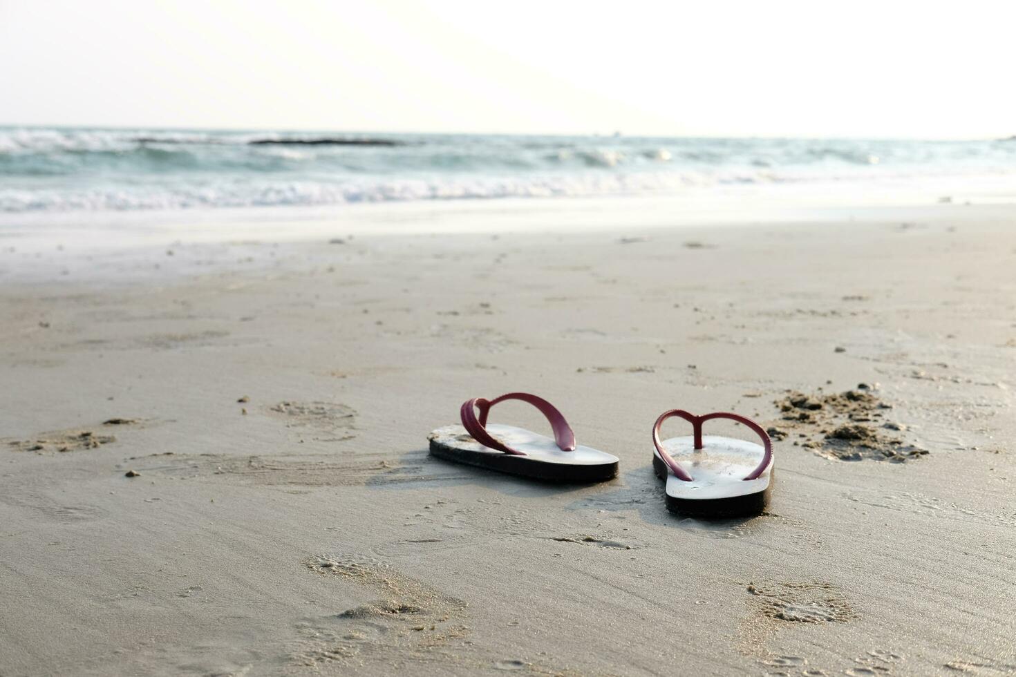 sandálias e sapatos pegadas em a de praia e azul mar. foto