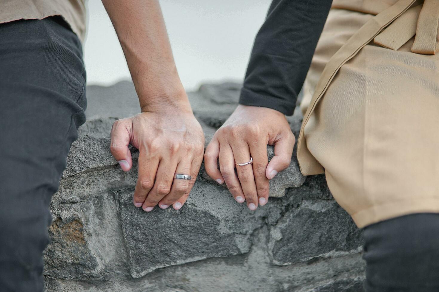 uma casal segurando mãos em uma Rocha parede foto