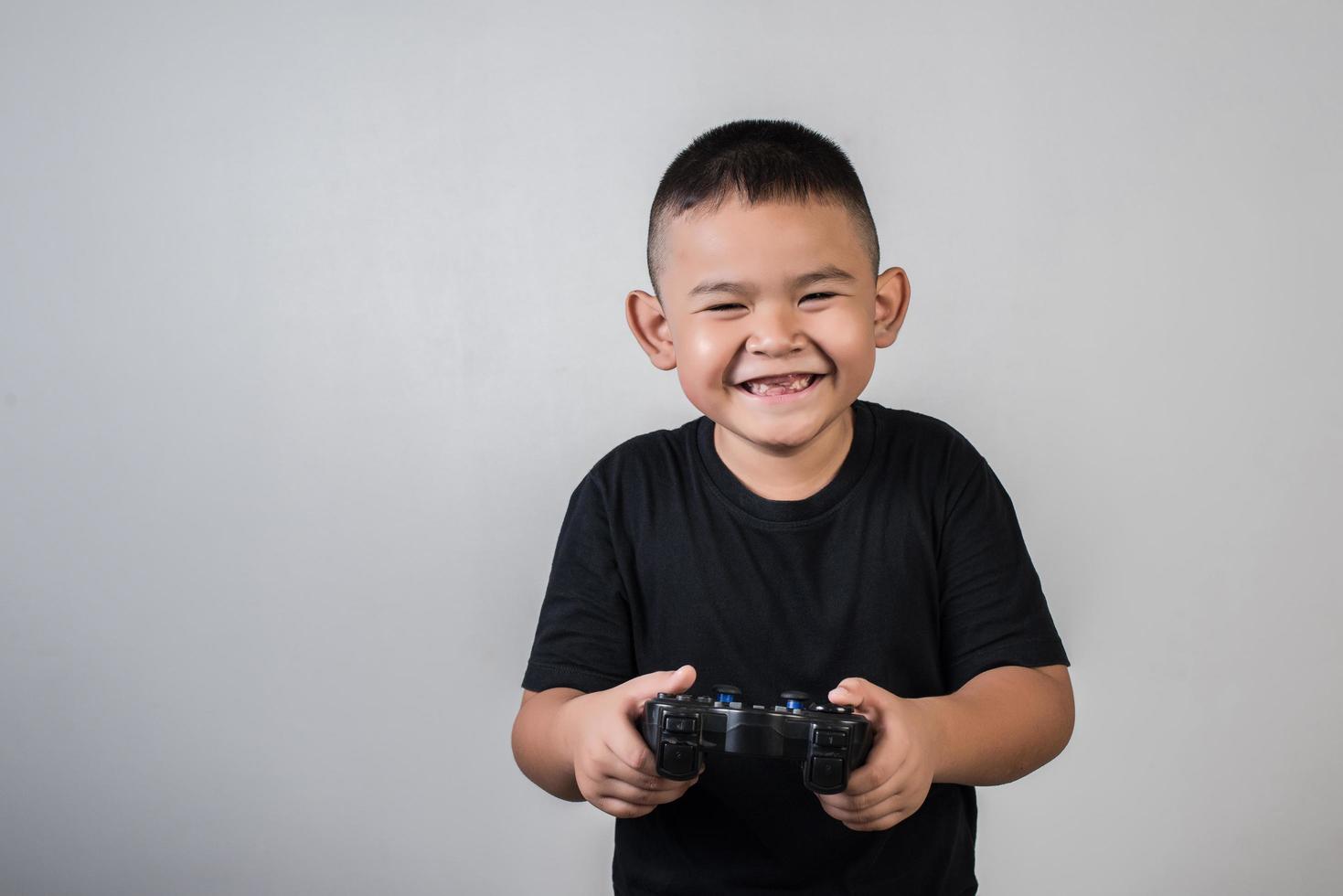 menino feliz jogando computador com um controlador em estúdio foto