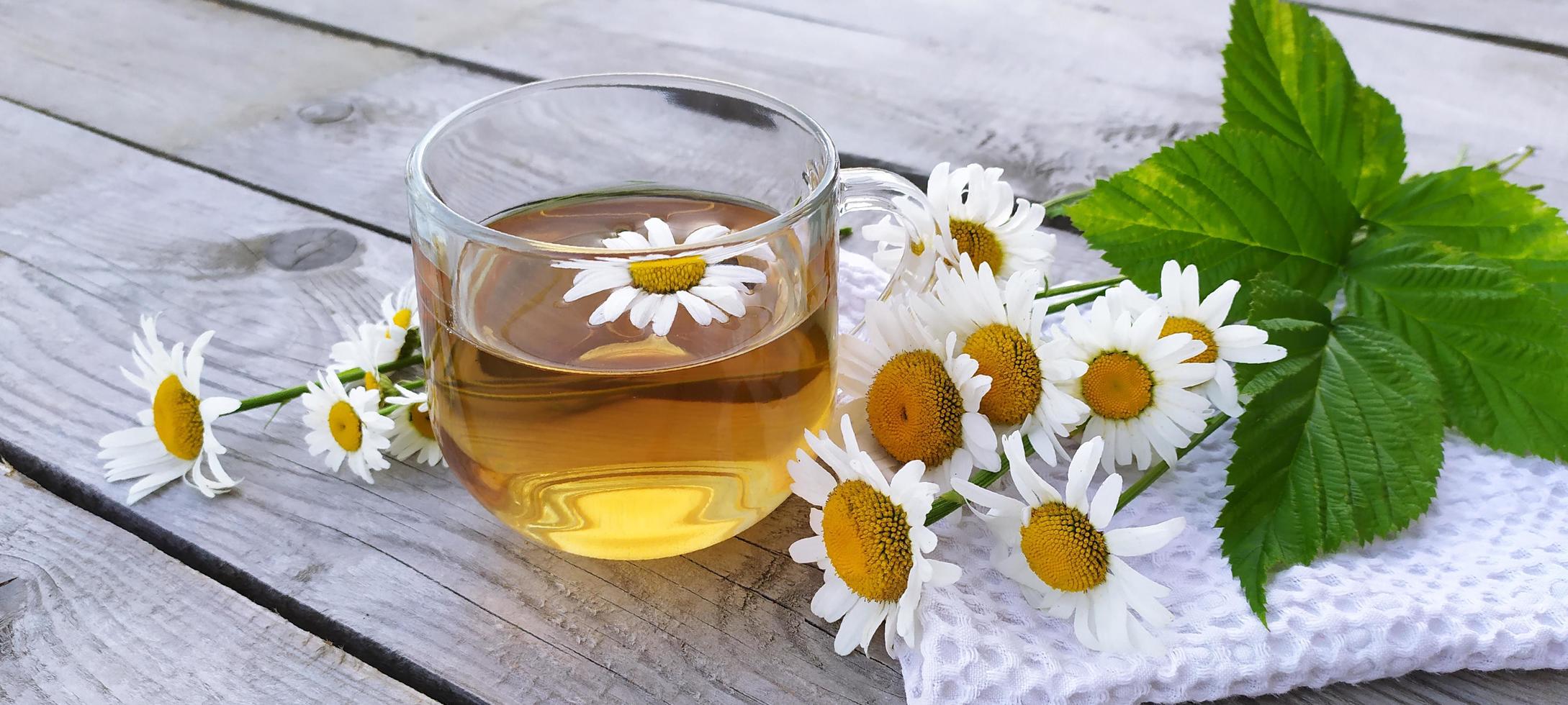 chá aromático de camomila em copo de vidro com fundo de madeira foto