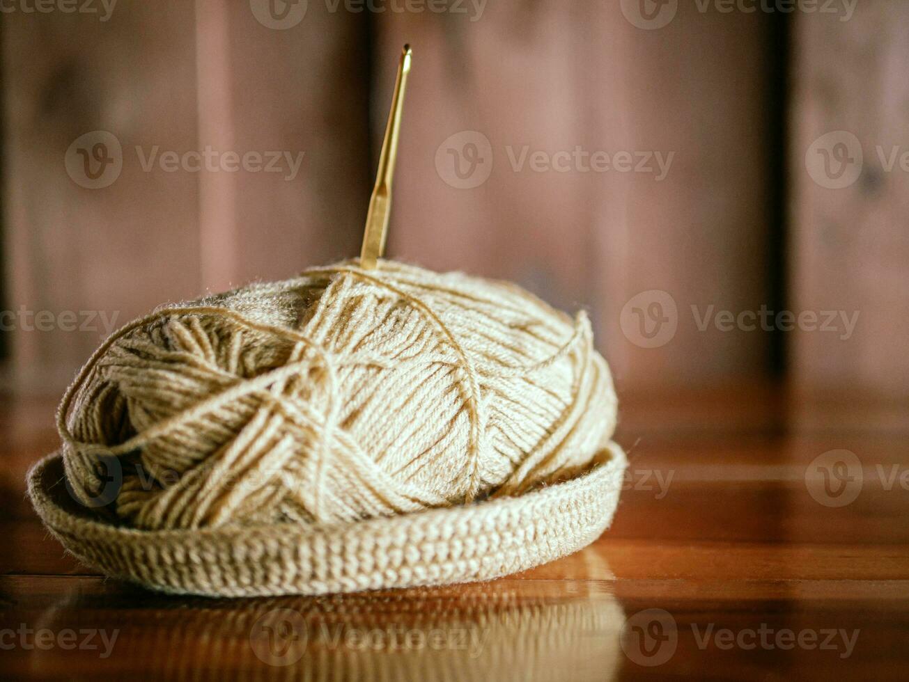 uma fio com uma tricô agulha preso dentro isto mentiras em uma de madeira mesa, hobby trabalhos manuais com fio, mão feito. foto