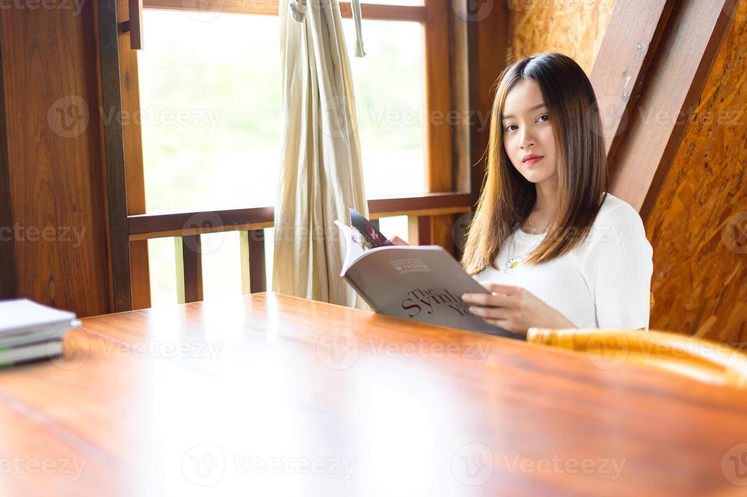 linda mulher sentada em um café lendo um livro foto