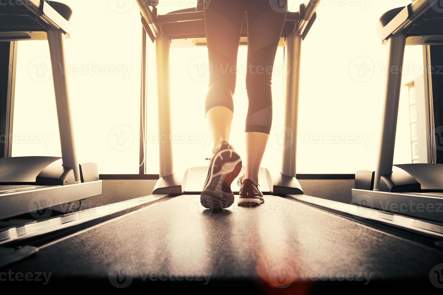 parte inferior do corpo na parte das pernas da garota fitness correndo na máquina de corrida foto