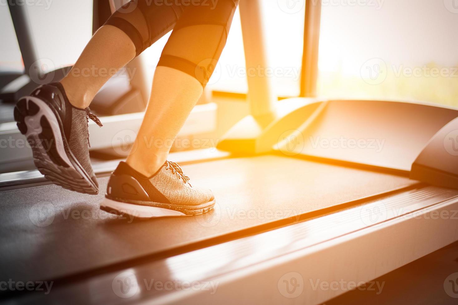 parte inferior do corpo na parte das pernas da garota fitness correndo na esteira foto