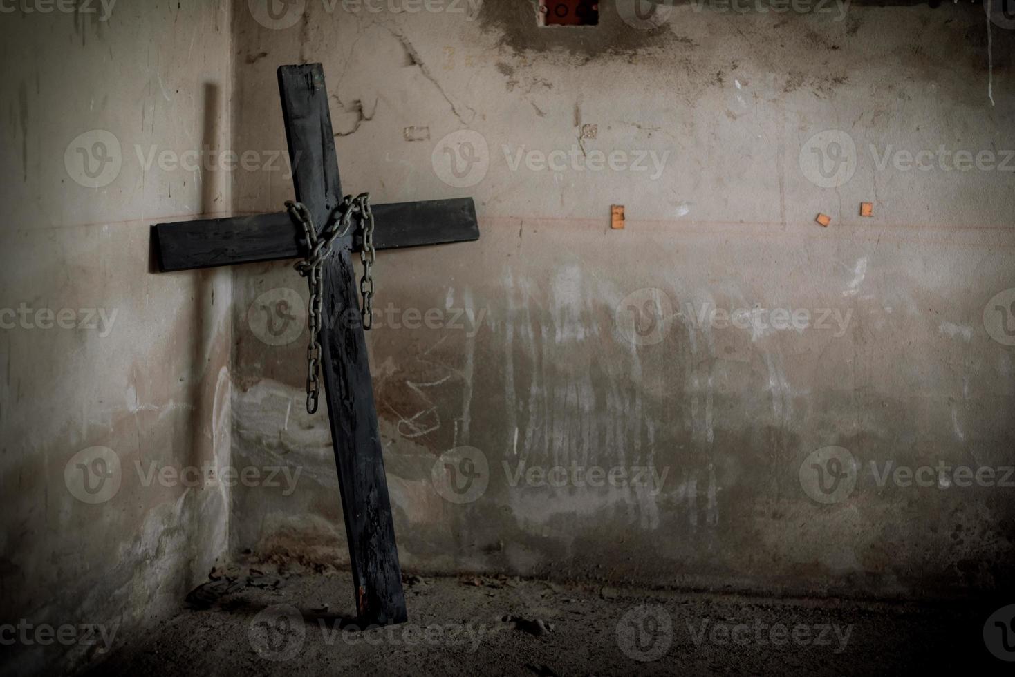 crucifixo preto contra a parede com corrente de aço suspensa e arma foto