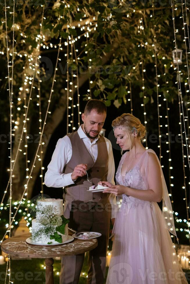 noivos alegremente cortam e provam o bolo de casamento foto