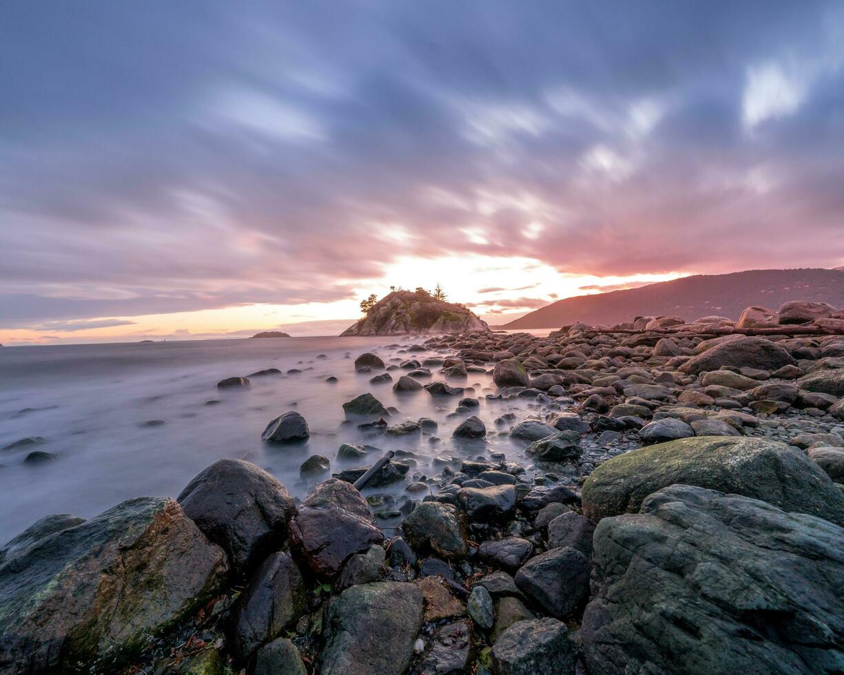 uma grandes exposição fotografia do uma rochoso litoral às pôr do sol foto