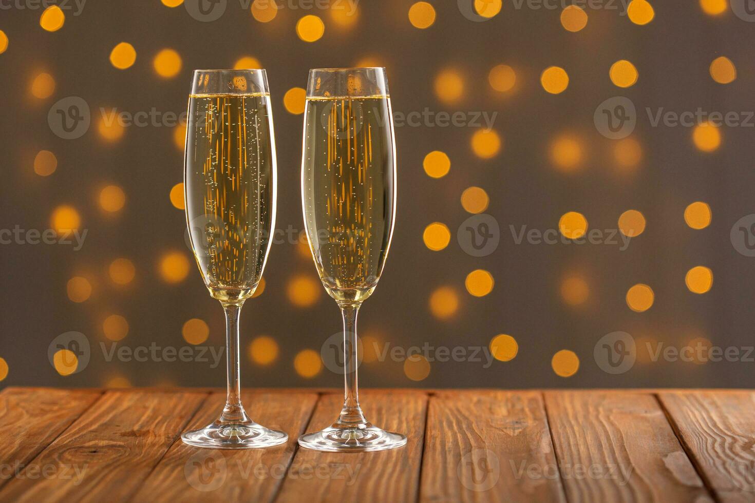 óculos com champanhe em uma de madeira fundo contra uma bokeh fundo do luzes foto