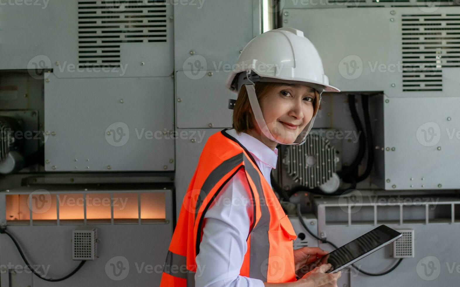 fábrica engenheiro mulher vestindo capacete de segurança segurança colete trabalhador às trabalhos industrial usando dados tábua examinando qualidade projeto eletrônico e sistema fabricação, planejamento Produção desenvolvimento máquina foto