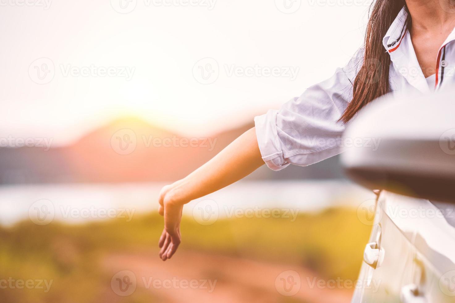 mulher feliz acenando com a mão do lado de fora do carro com janela aberta foto