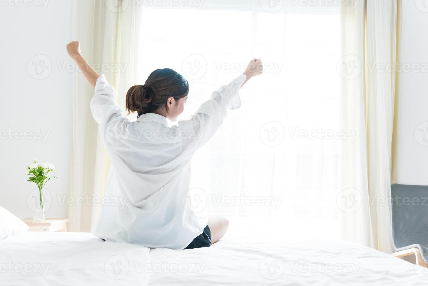 vista traseira de mulher se alongando pela manhã após acordar foto