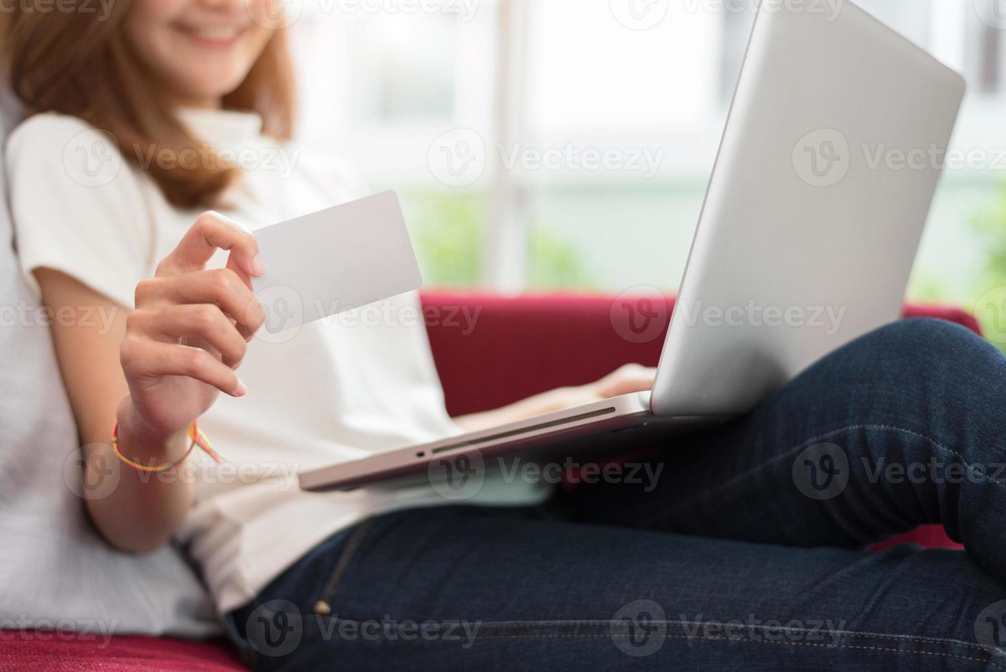 Mulher asiática bonita usando tablet e mostrando modelo de cartão de crédito em branco foto