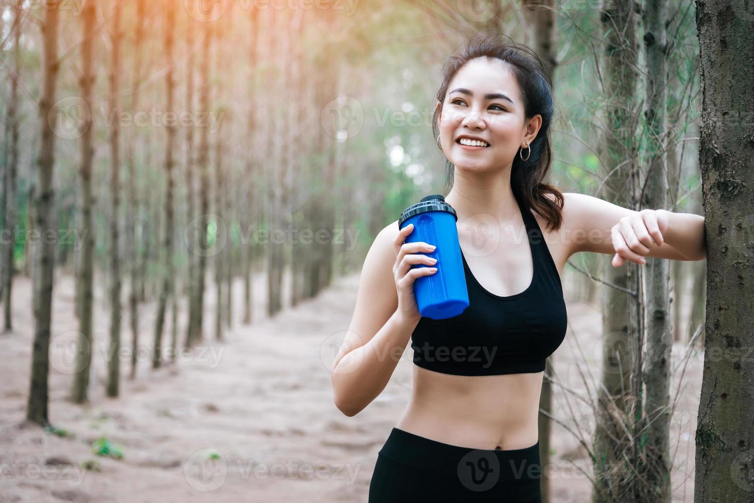 Mulher asiática bonita bebendo água na floresta foto