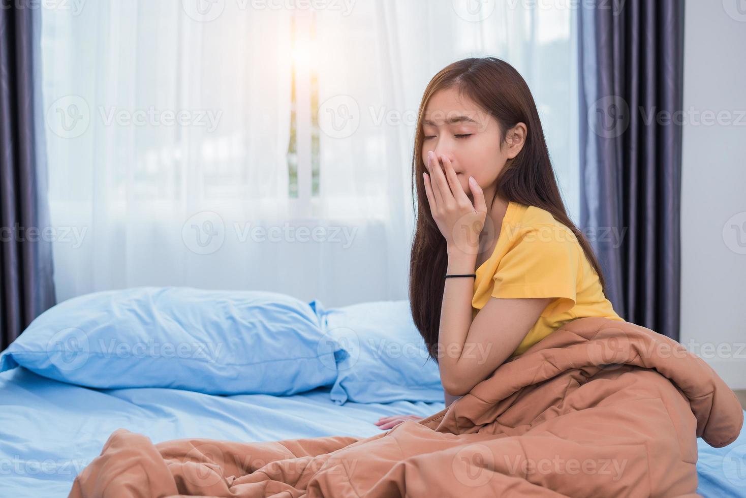 mulher asiática levantando-se de manhã em postura preguiçosa no quarto foto