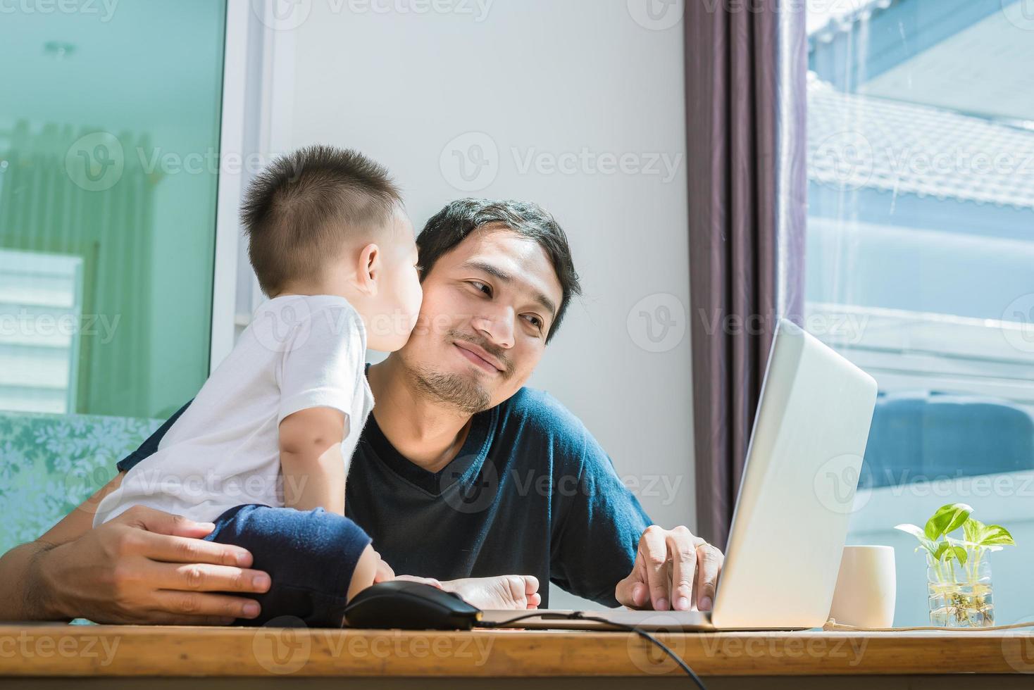 filho beijando o pai enquanto usa a internet. pessoas e estilos de vida foto