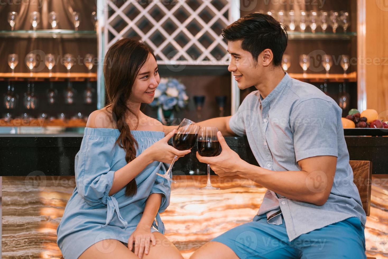 casais jovens asiáticos tilintando taças de vinho em bar doméstico foto