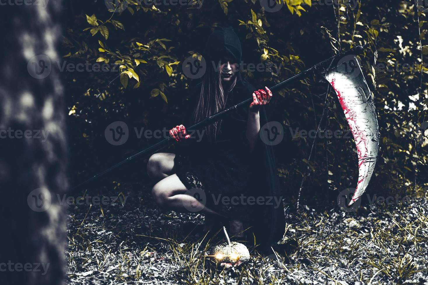 bruxa demoníaca sentada e segurando ceifeira foto