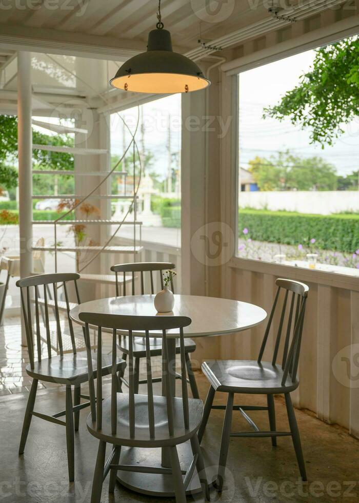 de madeira mesa com cadeiras com luminária iluminação dentro cafeteria foto