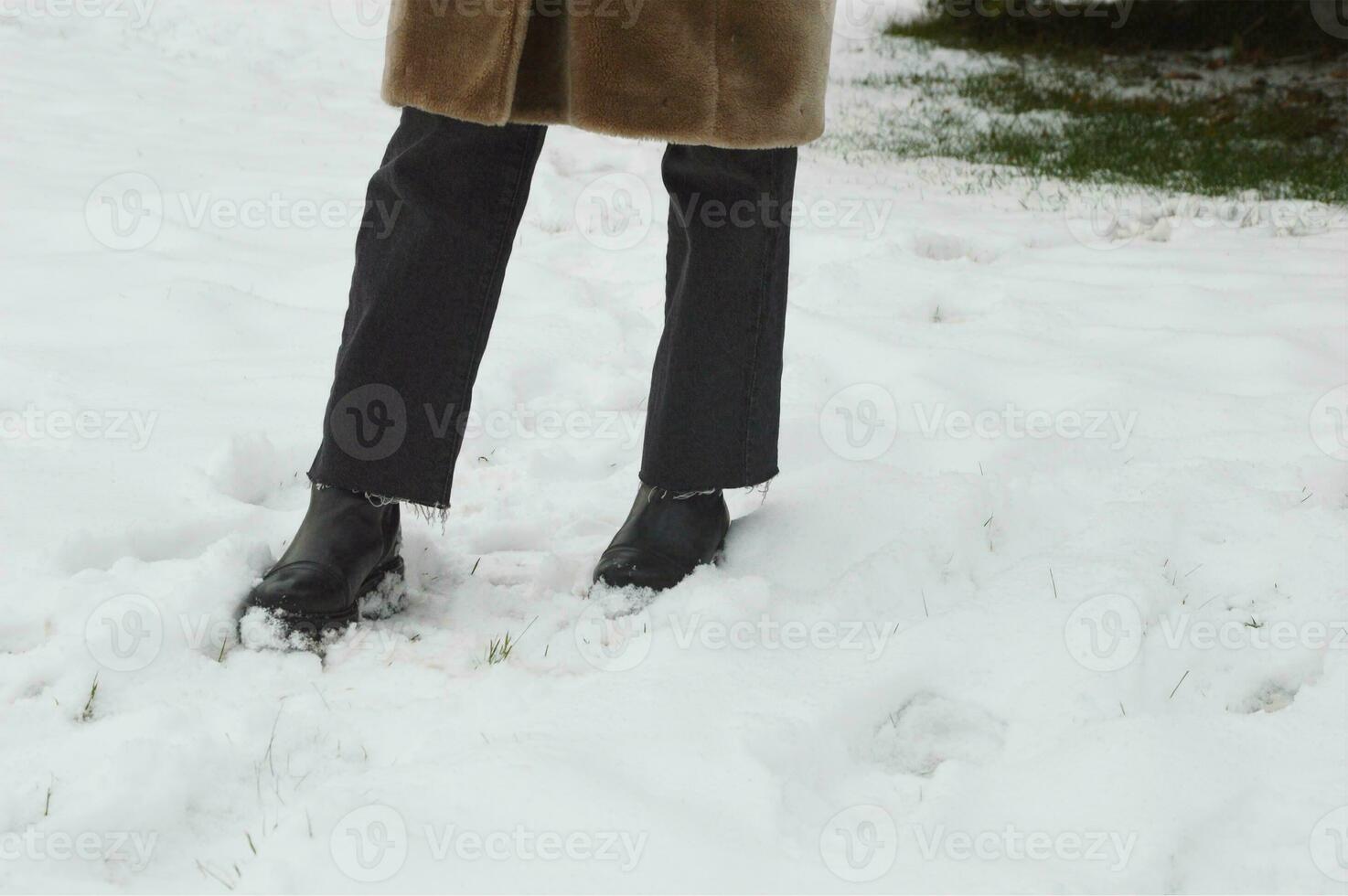 pernas do uma jovem mulher dentro Preto calças e elegante à moda Preto couro inverno tornozelo chuteiras em a aberto neve. inverno sapato, roupas. foto