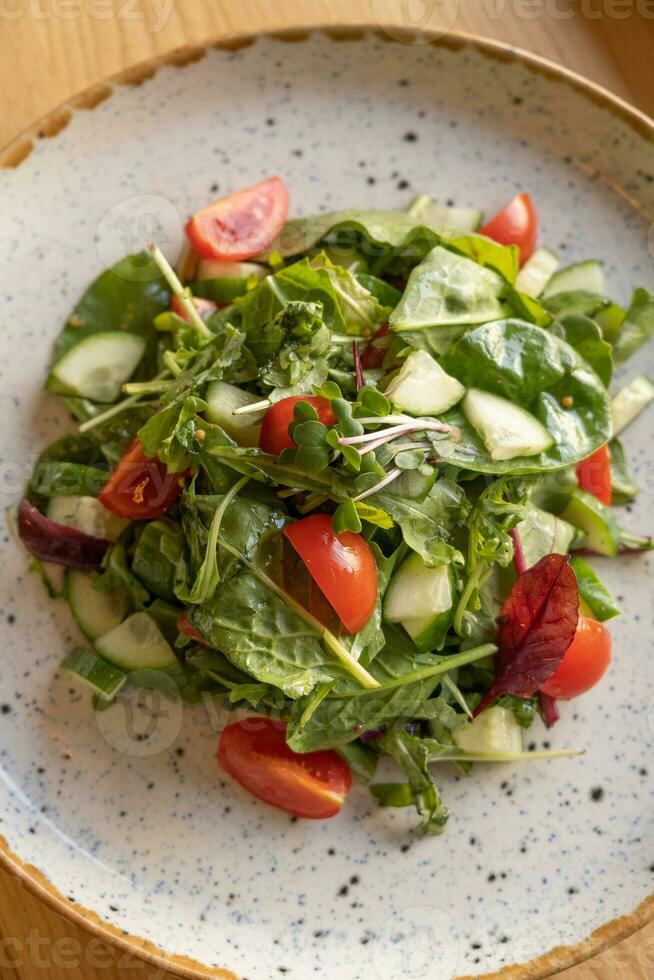 fresco salada com Rúcula, cereja tomates, pepinos dentro uma prato fechar acima foto