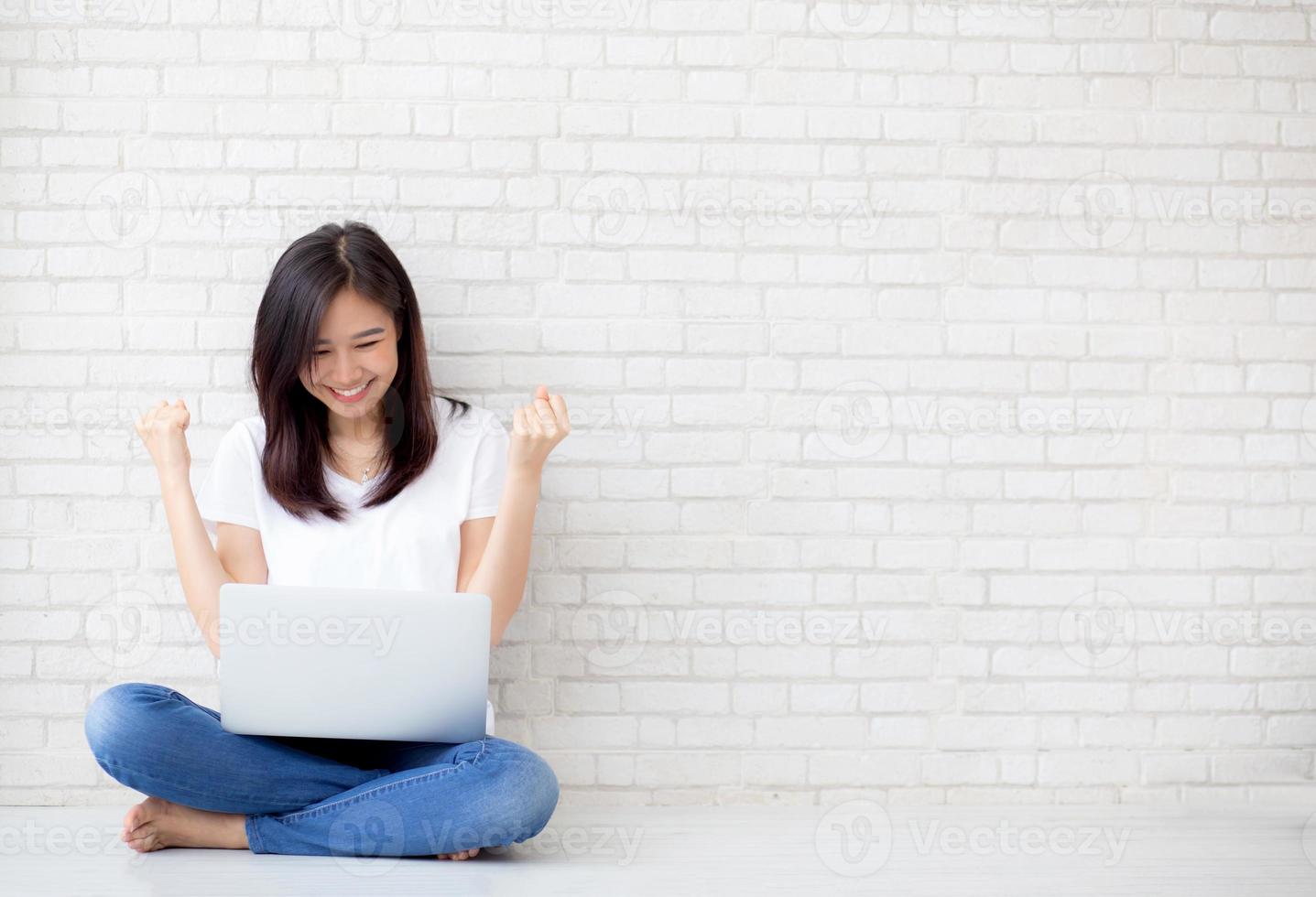 jovem mulher asiática, animada e feliz com o sucesso com o laptop. foto