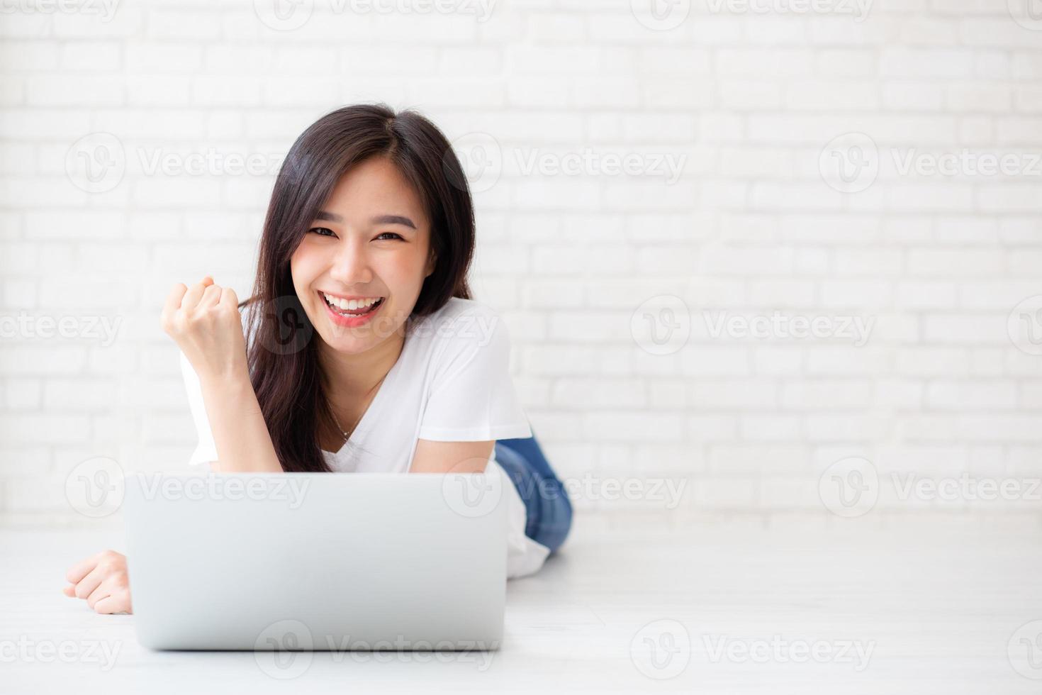 jovem mulher asiática, animada e feliz com o sucesso com o computador portátil. foto