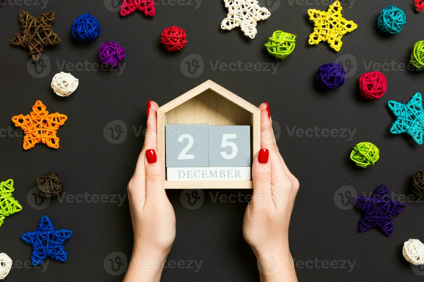 vista superior das mãos femininas segurando o calendário em fundo preto. dia vinte e cinco de dezembro. decorações de férias. conceito de tempo de natal foto