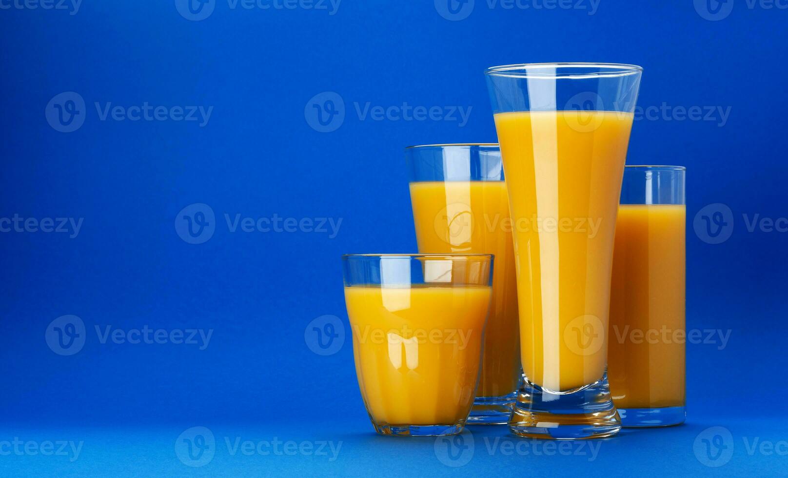 copos de suco de laranja em fundo azul com espaço de cópia foto