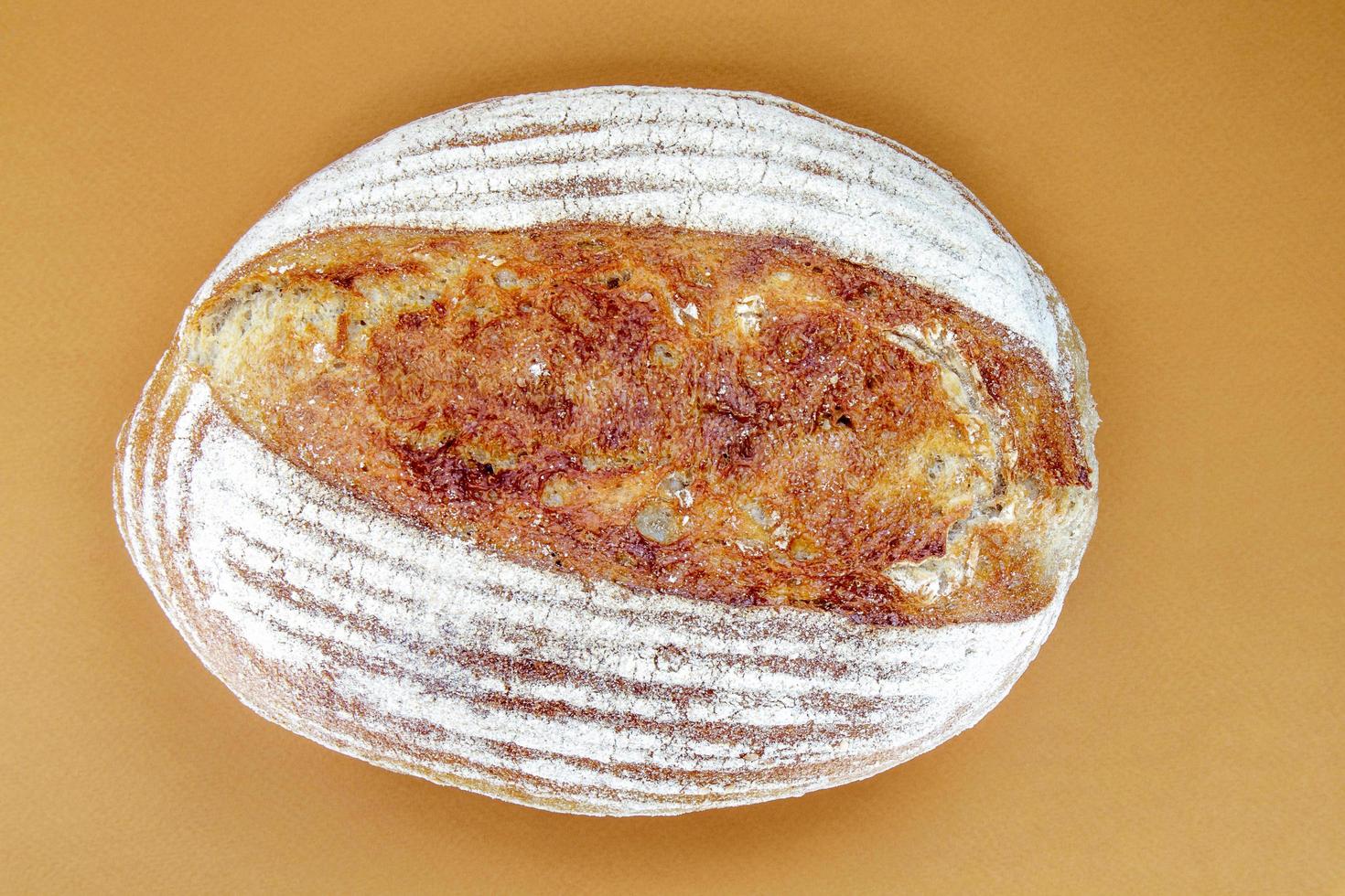 pão recém-assado com massa fermentada orgânica isolado no marrom foto