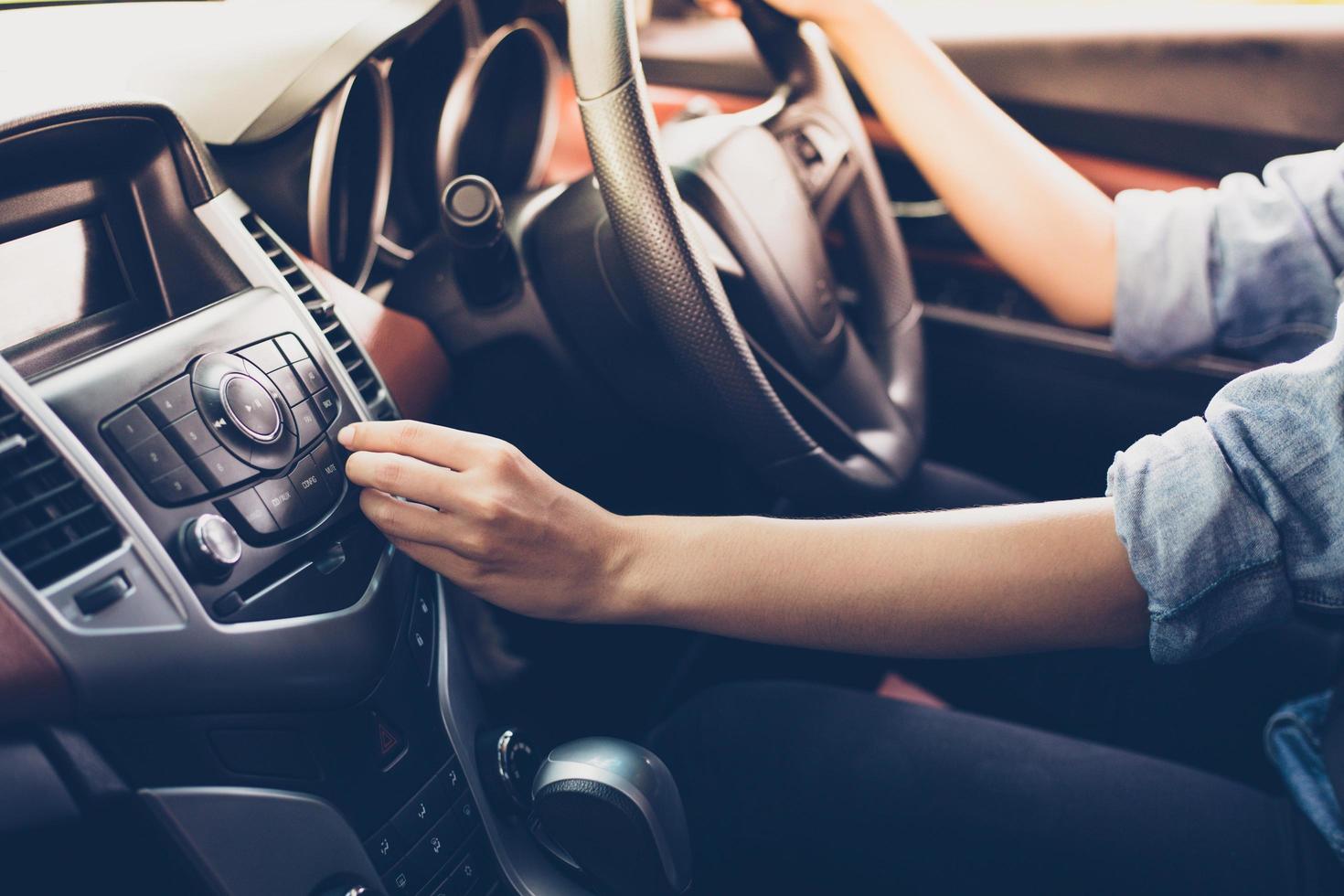 mulheres asiáticas pressionam o botão do rádio do carro para ouvir música. foto