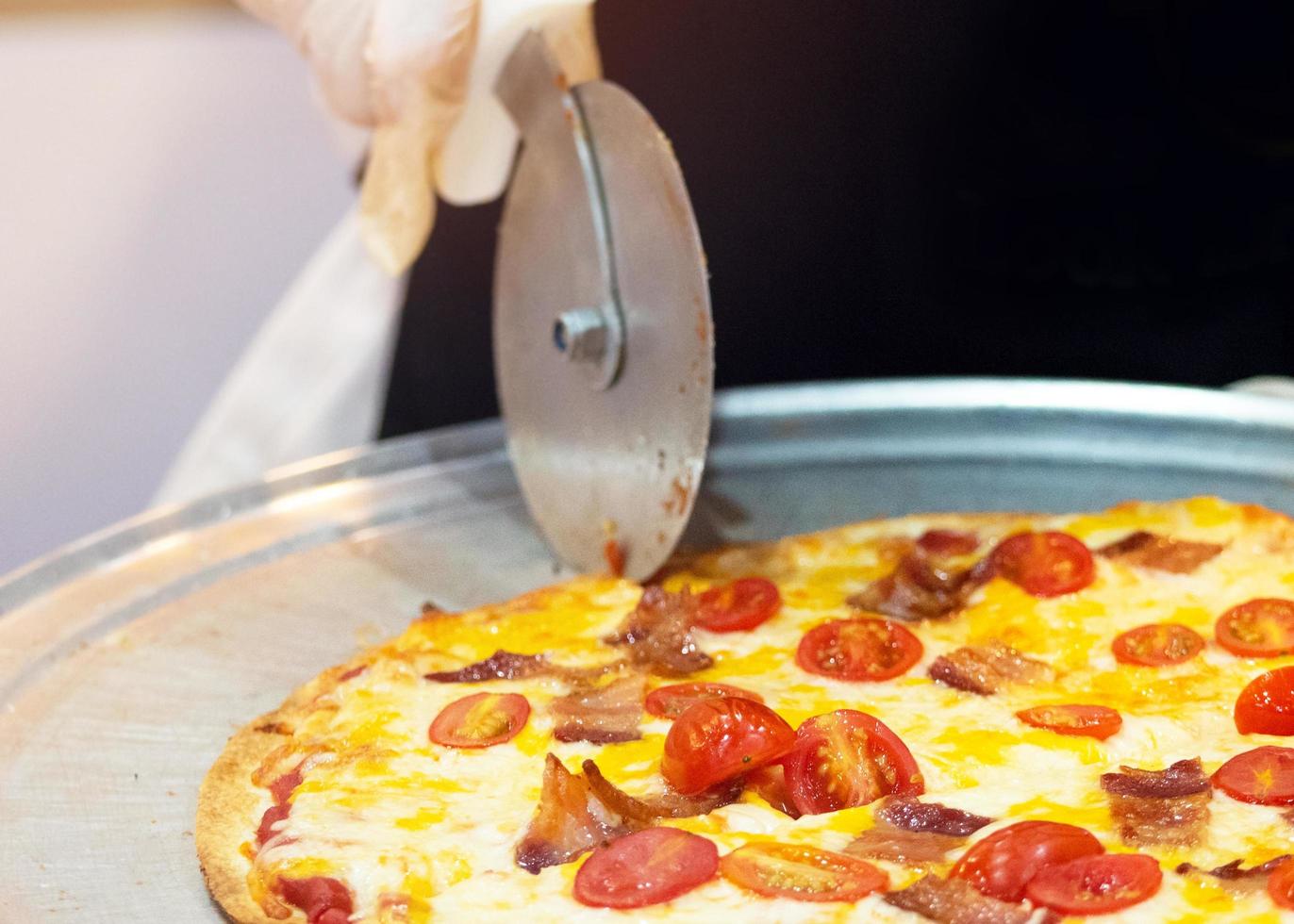 closeup mão do chef cortando pizza na cozinha foto