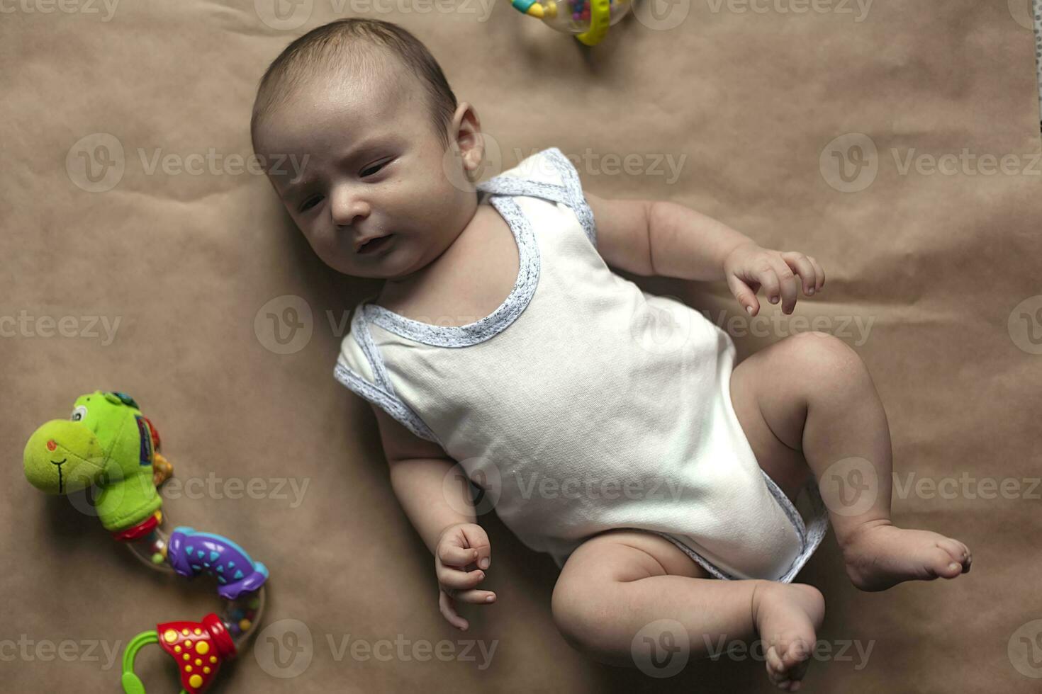 recém-nascido bebê Garoto deitado com brinquedos. fechar-se do adorável fofa recém-nascido bebê Garoto do dois meses e brinquedos. adorável criança jogando foto