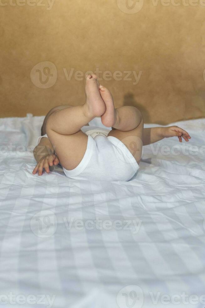 6-8 meses de idade bebê Garoto deitado de brincadeira dentro cama. encantador 6-7 mês pequeno bebê dentro branco maiô. bebê Garoto dentro branco roupa de cama. cópia de espaço foto