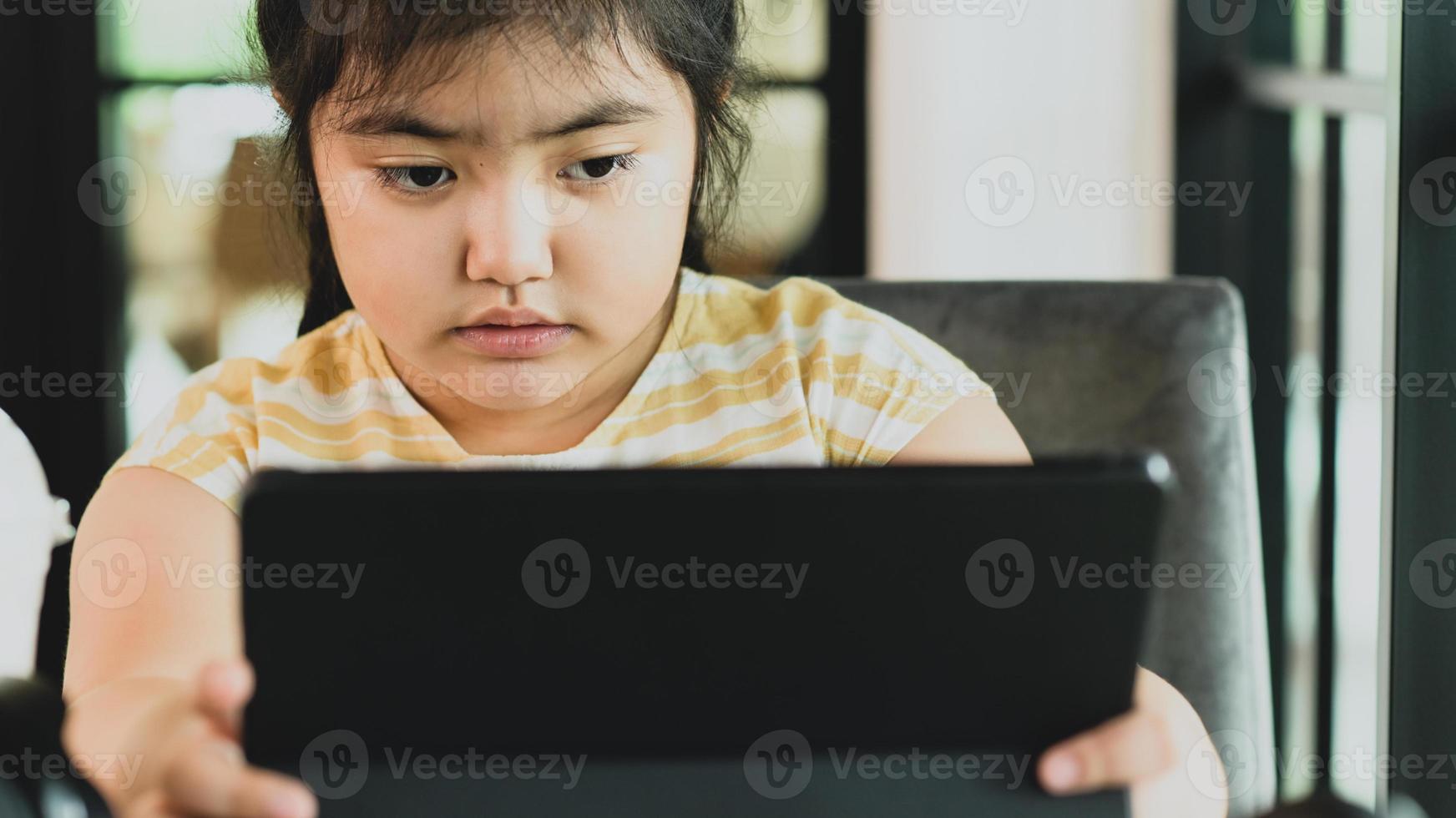 menina criança olhou para o tablet com os olhos cansados de estudar online. foto