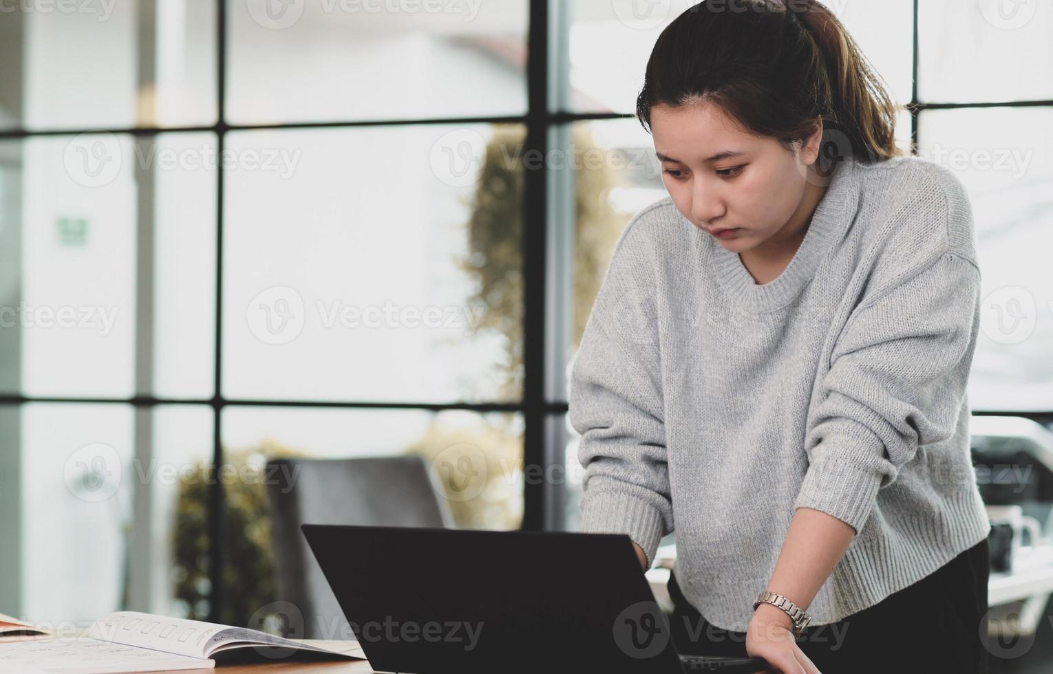 uma adolescente olha para a tela do laptop em cima da mesa. foto