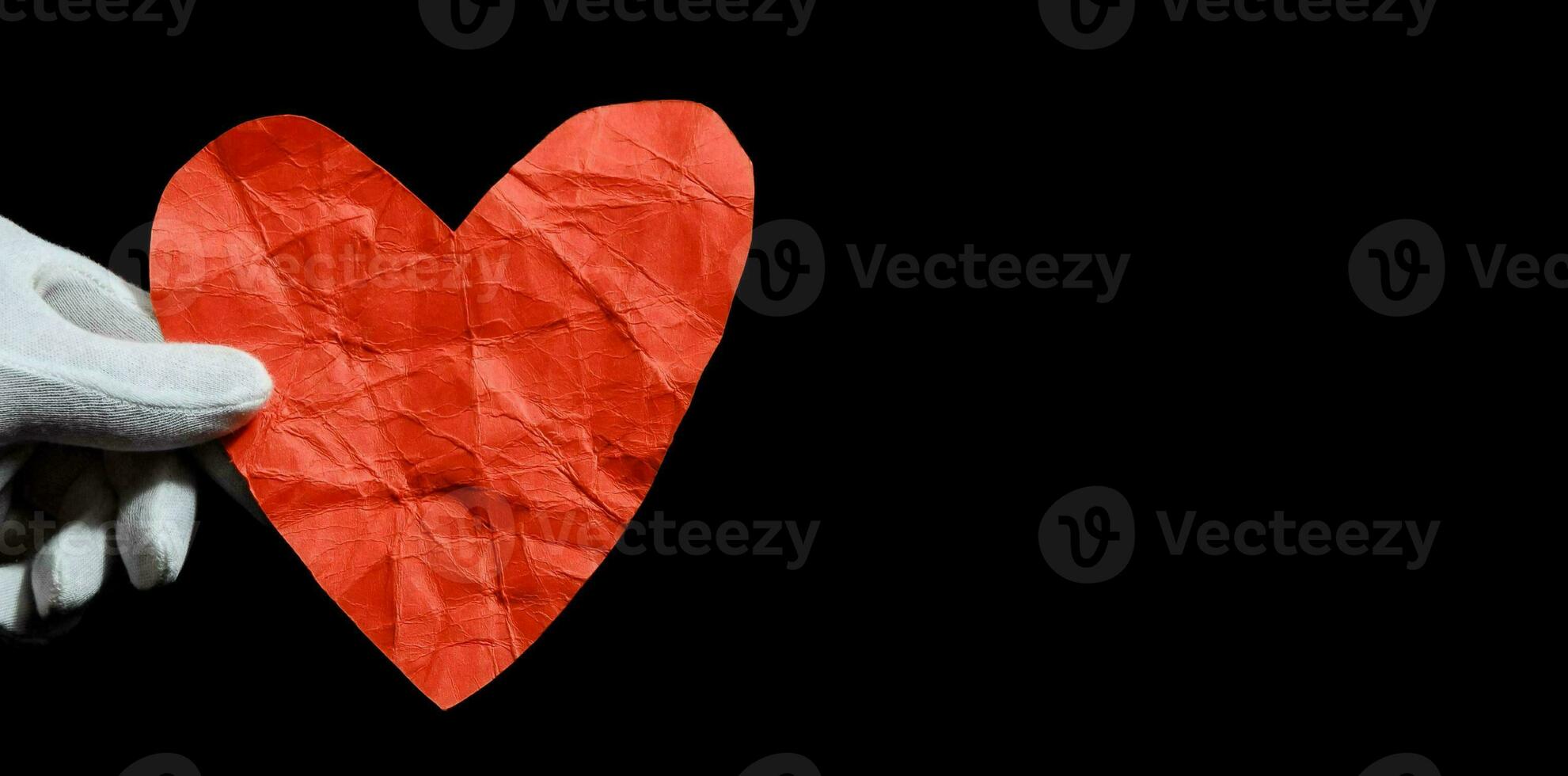 uma mão segurando uma vermelho coração em forma papel foto