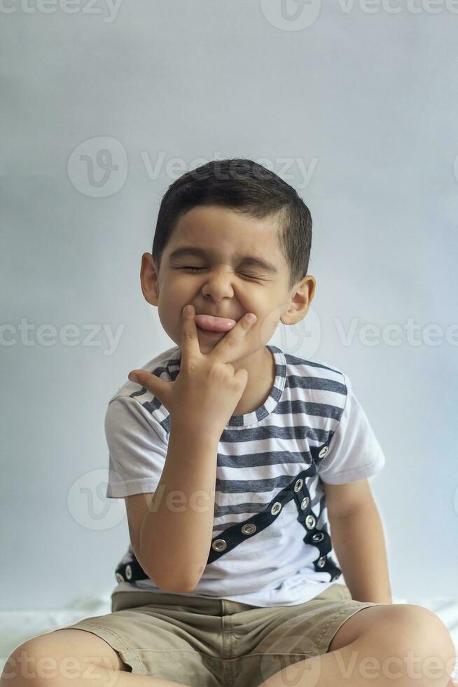 seis anos Garoto retrato. inocente sorridente pequeno Garoto em cinzento fundo. pequeno Garoto contorce-se dele face. pessoas, infância estilo de vida conceito. foto