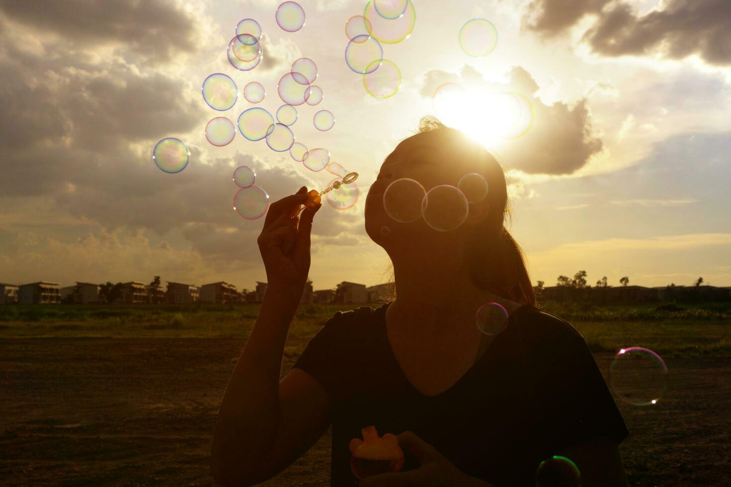 uma sul leste ásia menina é sopro bolhas para dentro a ar às pôr do sol. foto