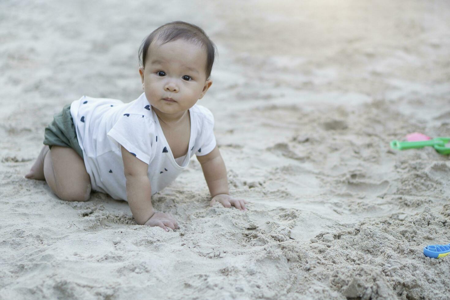 ásia criança pequena bebê tailandês menina jogando com areia foto