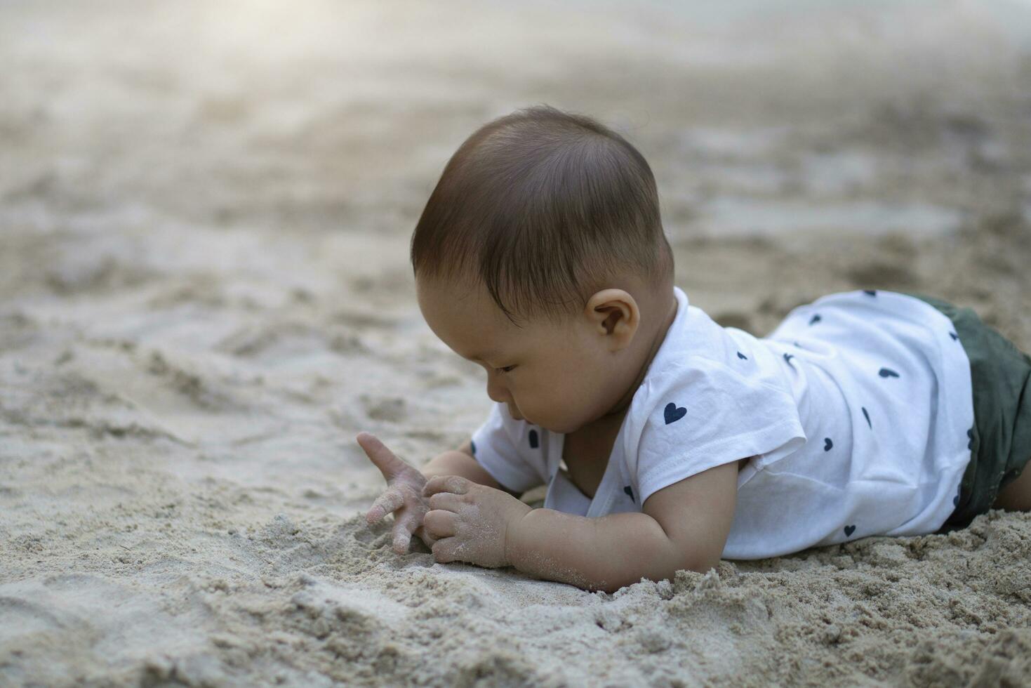 ásia criança pequena bebê tailandês menina jogando com areia foto