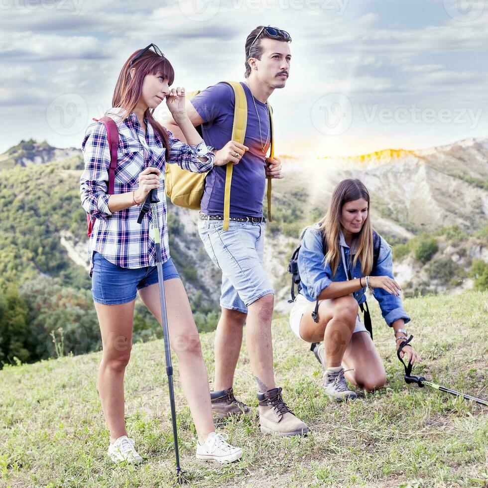 grupo do jovem caminhantes caminhando em direção a a horizonte sobre a montanha foto