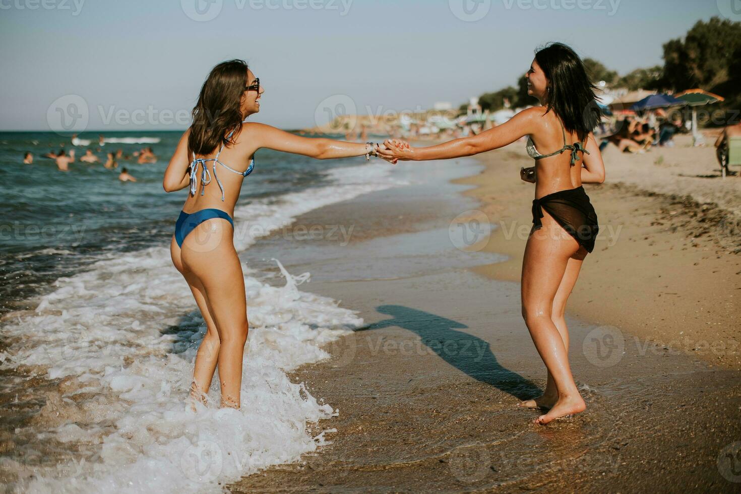 dois bonita jovem mulher tendo Diversão em a beira-mar foto