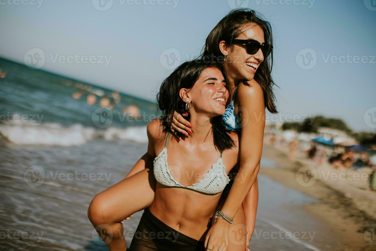 dois bonita jovem mulher tendo Diversão em a beira-mar foto