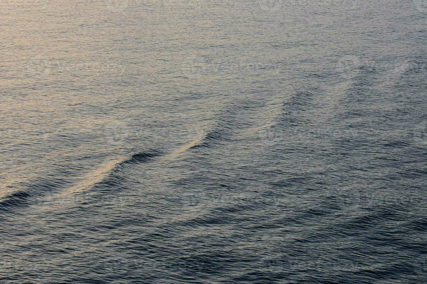 uma barco é Navegando através a oceano às pôr do sol foto
