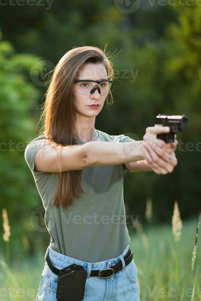 jovem menina com uma arma de fogo dentro dele mãos fotos dentro natureza